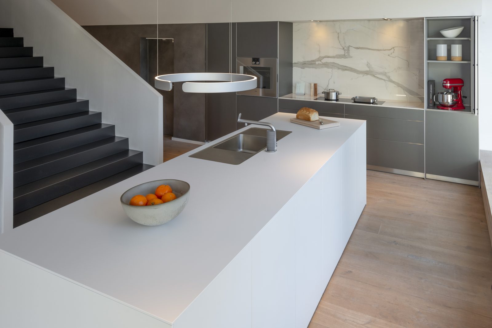 White kitchen island with staircase and marble splashback